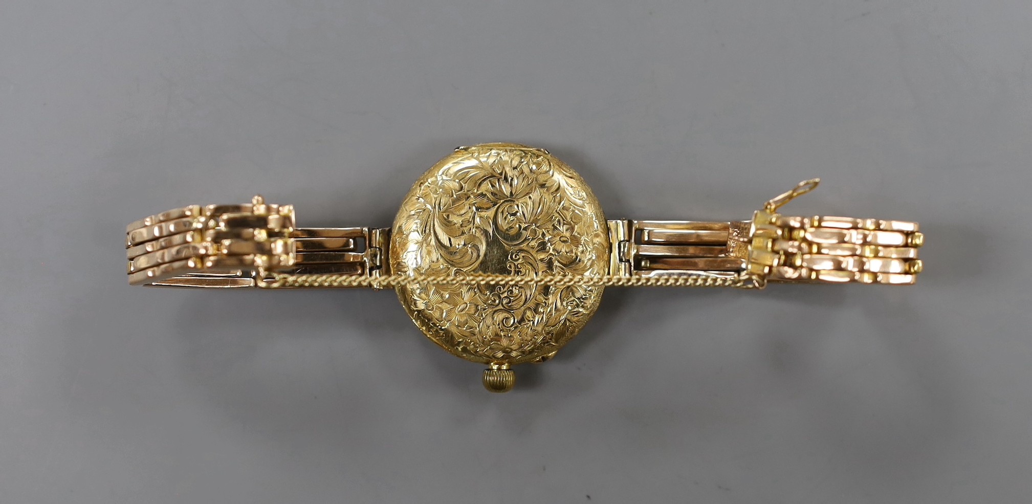 An early 20th century engraved 18ct gold fob watch, now converted to a wrist watch on a later expanding yellow metal bracelet
